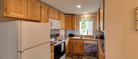A kitchen with wooden cabinets, a white refrigerator, a microwave, an oven, and a dishwasher.