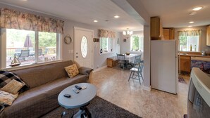 Ein gemütliches Wohnzimmer mit einer Couch, einem runden Couchtisch und einem Essbereich mit Tisch und Stühlen.
