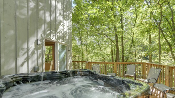 A hot tub on a wooden deck surrounded by trees.