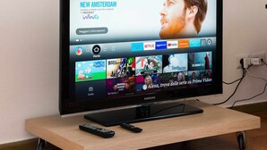 A Samsung TV on a wooden stand with remote controls, displaying a streaming service interface with various channels and apps. - Home Roman Center Neptune (Nettuno)