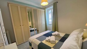 A hotel room with a bed, a desk, and a wardrobe. - Home Roman Center Neptune (Nettuno)