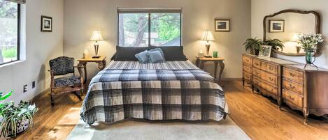 A bedroom with a large bed, two bedside tables with lamps, a dresser, a chair, and a ceiling fan.