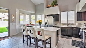 A modern kitchen with a central island, dark cabinets, and a view of the outdoors. - Group Fun in Glendale! Getaway w/ Private Pool (Glendale)