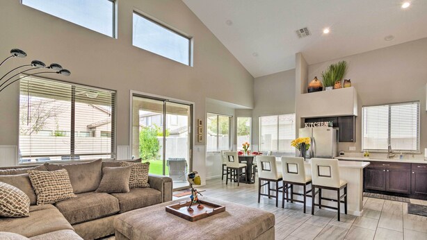 A spacious living room with a large sectional sofa, a coffee table, and a dining area with a kitchen in the background. - Group Fun in Glendale! Getaway w/ Private Pool (Glendale)