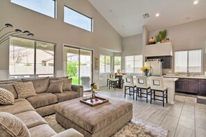 A spacious living room with a large sectional sofa, a coffee table, and a dining area with a kitchen in the background. - Group Fun in Glendale! Getaway w/ Private Pool (Glendale)