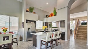 A spacious kitchen with a central island, modern appliances, and a dining area with chairs. - Group Fun in Glendale! Getaway w/ Private Pool (Glendale)