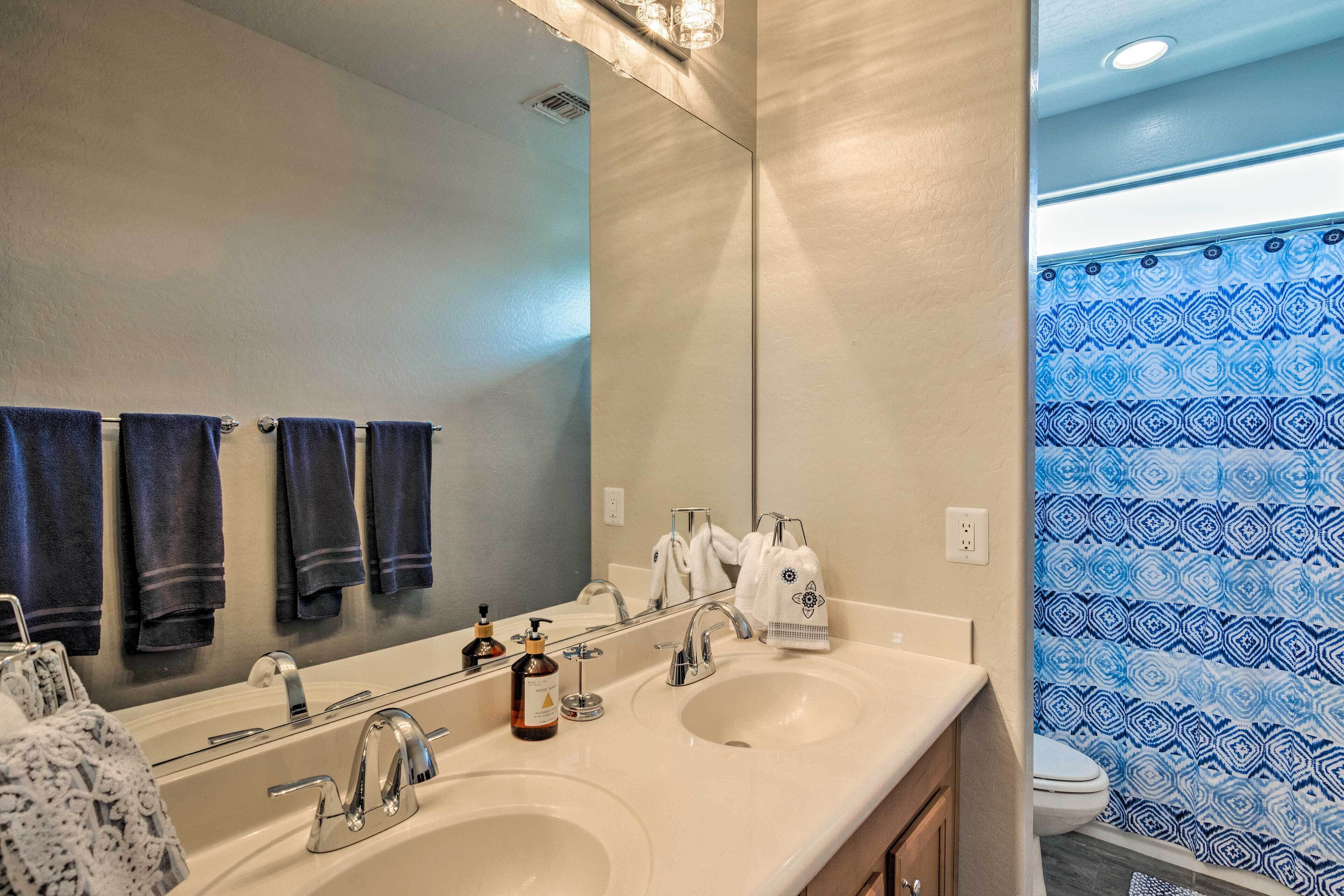 A bathroom with two sinks, a mirror, and a toilet.