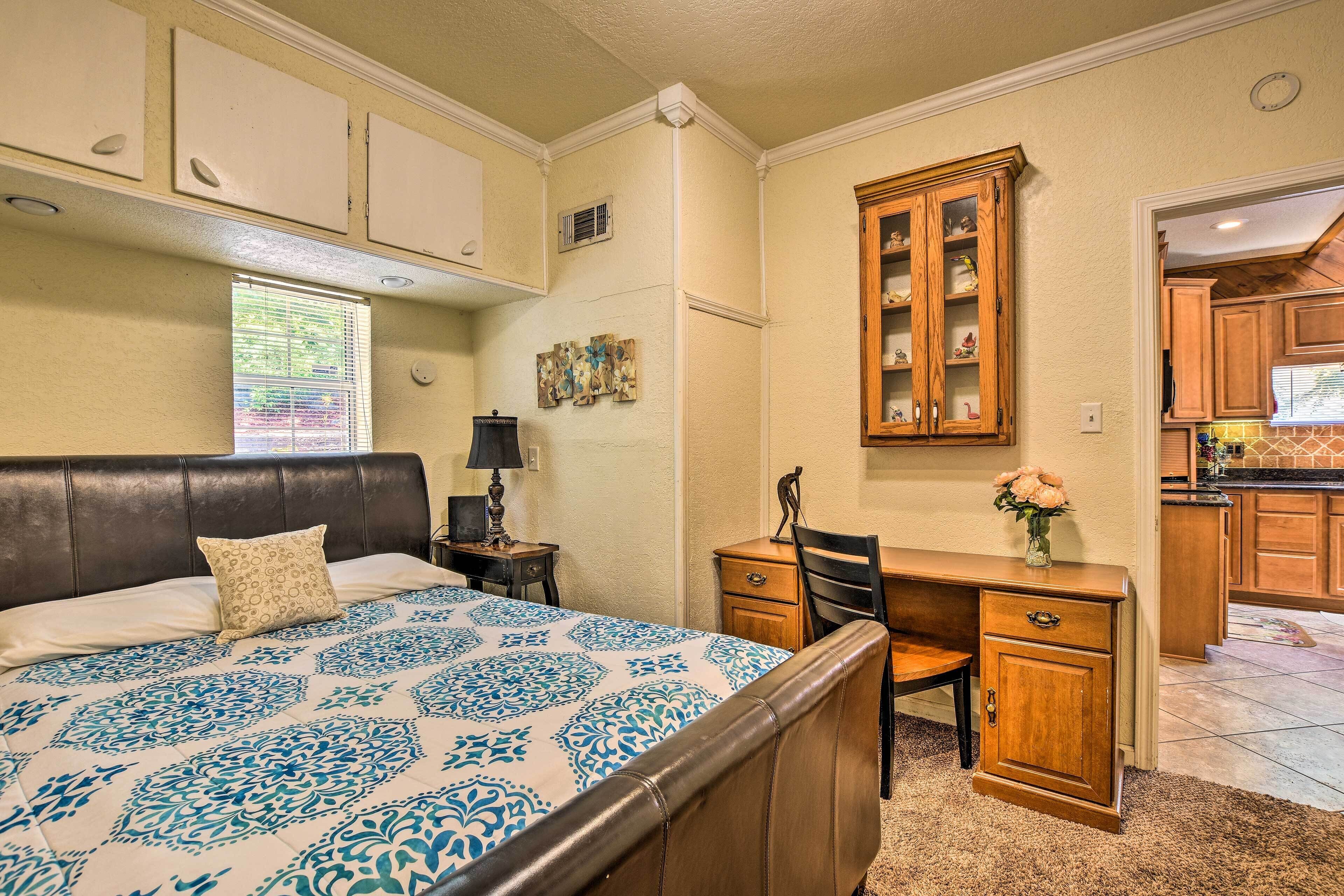 A bedroom with a bed, a desk, and a cabinet.