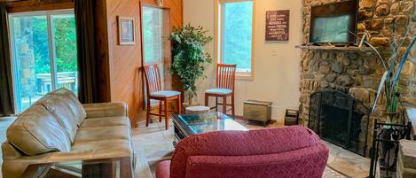 A cozy living room with a stone fireplace, leather sofa, and a red armchair.