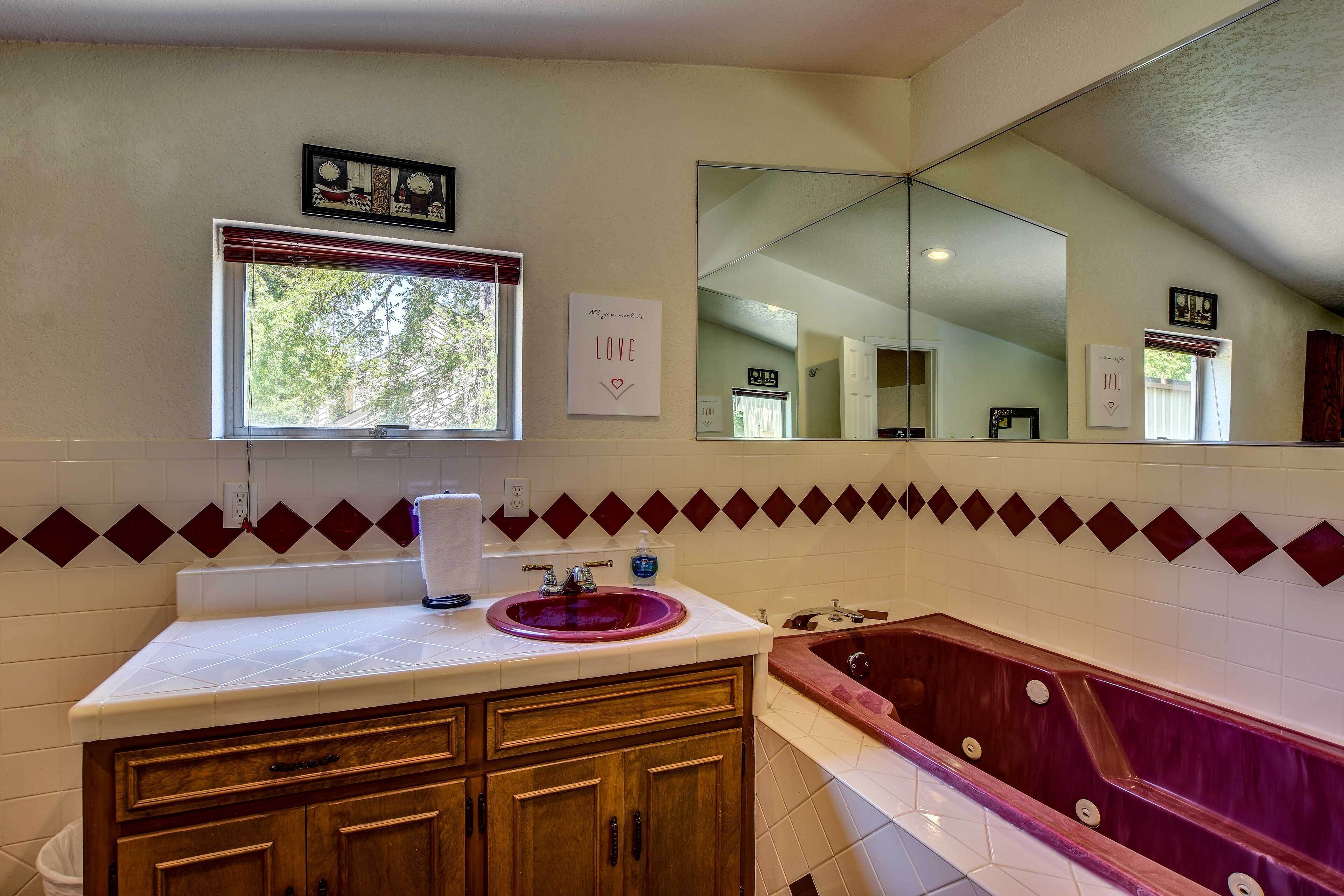 A bathroom with a wooden vanity, a large mirror, and a freestanding bathtub.