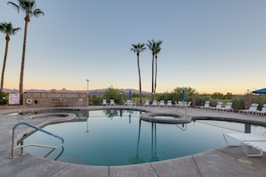 A swimming pool with lounge chairs and palm trees.