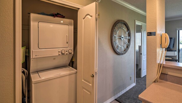 Une buanderie équipée d’un lave-linge et d’un sèche-linge, avec une horloge et un téléphone fixés au mur.