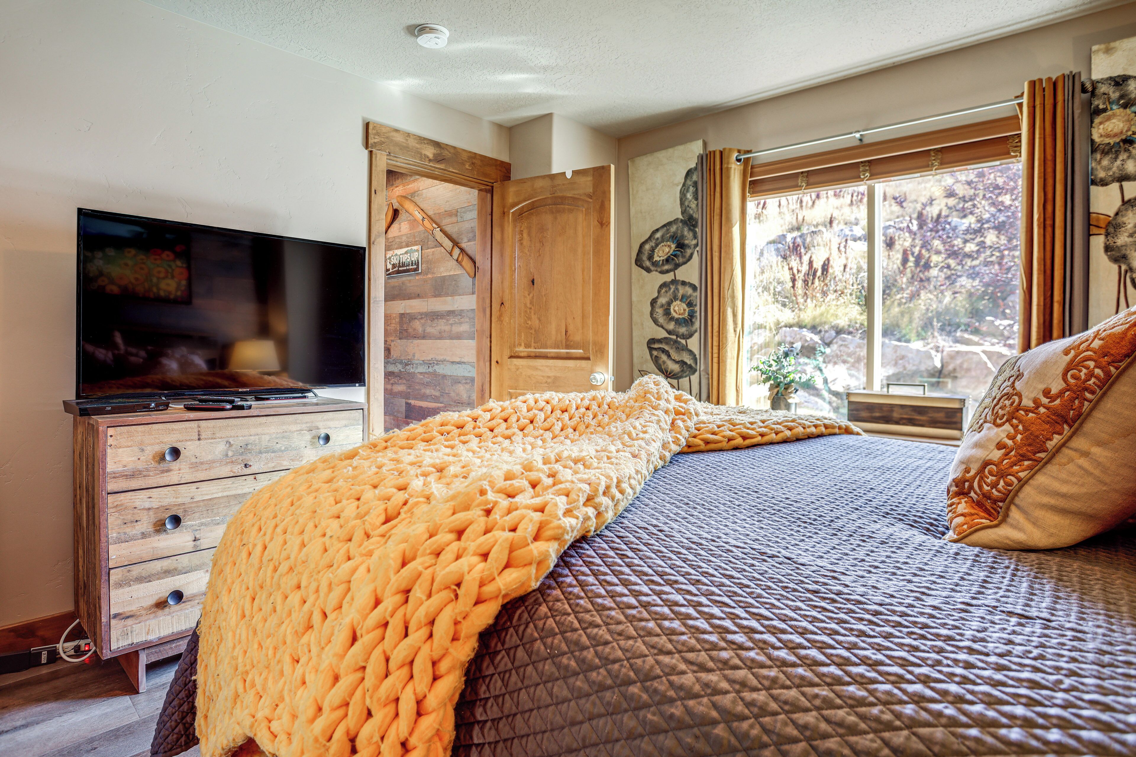 Une chambre à coucher avec un lit, une télévision, des meubles en bois et une fenêtre avec des rideaux.