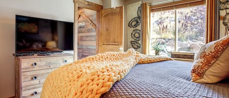Une chambre à coucher avec un lit, une télévision, des meubles en bois et une fenêtre avec des rideaux.