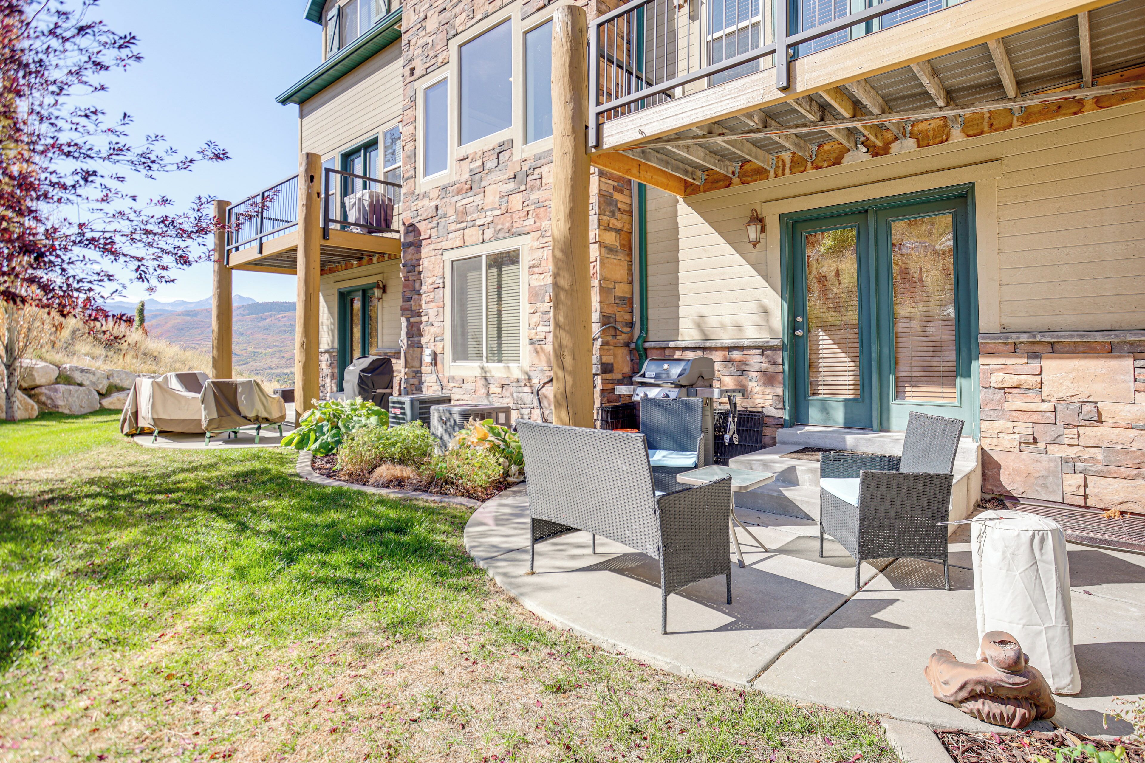A patio with outdoor furniture, a grill, and a stone building with a balcony.