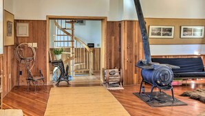 A rustic interior with wooden walls, a spiral staircase, a vintage stove, and a sofa. - Converted Historic Schoolhouse w/ Views! (Greybull)