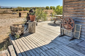 A wooden deck with rustic furniture, including a table and chairs, and a wheelbarrow. - Converted Historic Schoolhouse w/ Views! (Greybull)