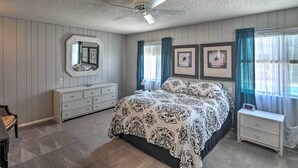 A bedroom with a bed, dresser, nightstand, and ceiling fan.