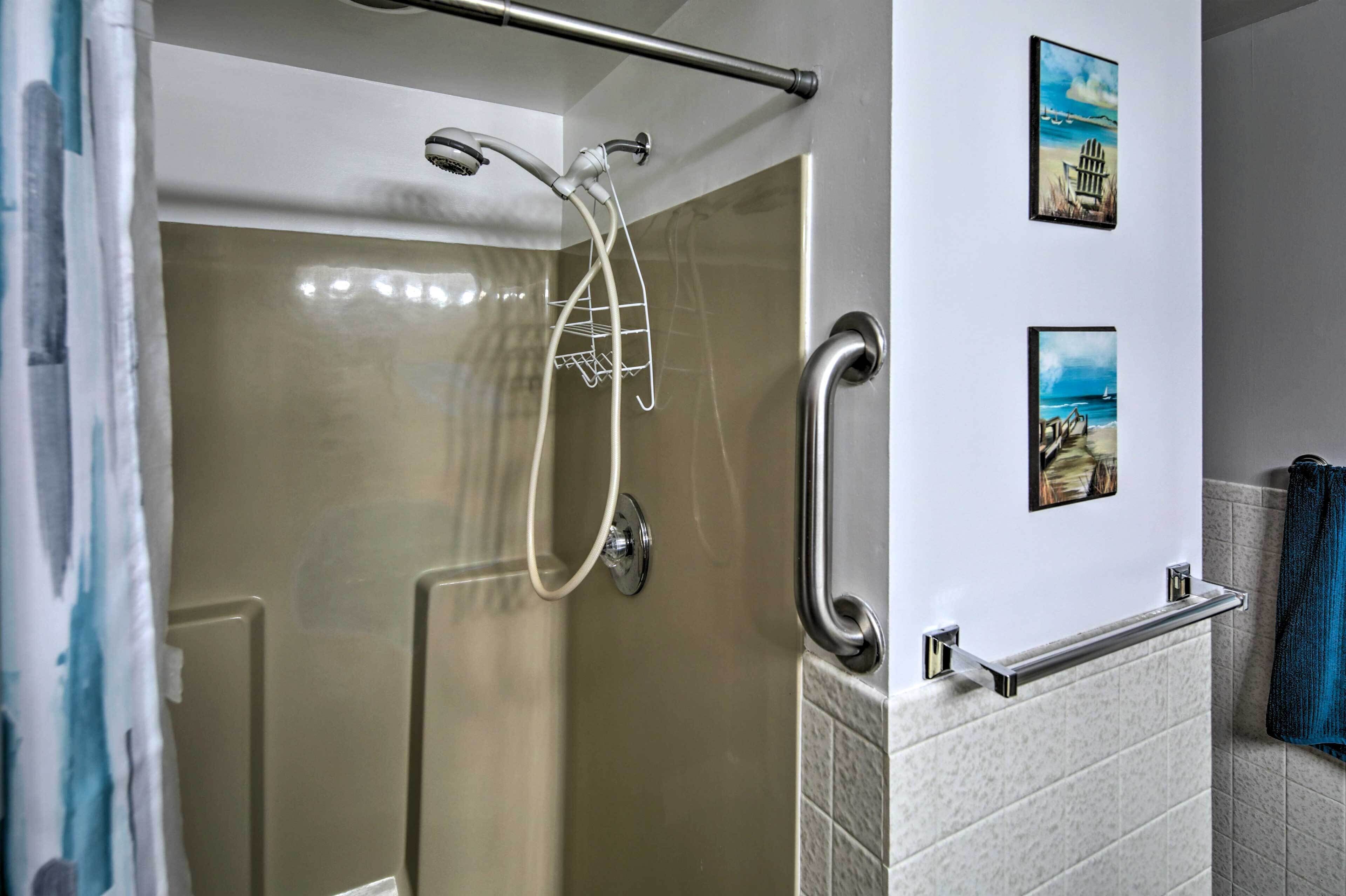Een moderne badkamer met een douchecabine van glas, een handdoekrek en twee ingelijste foto's aan de muur.
