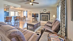 A spacious living room with a fireplace, leather sofas, a dining area, and a kitchen in the background.
