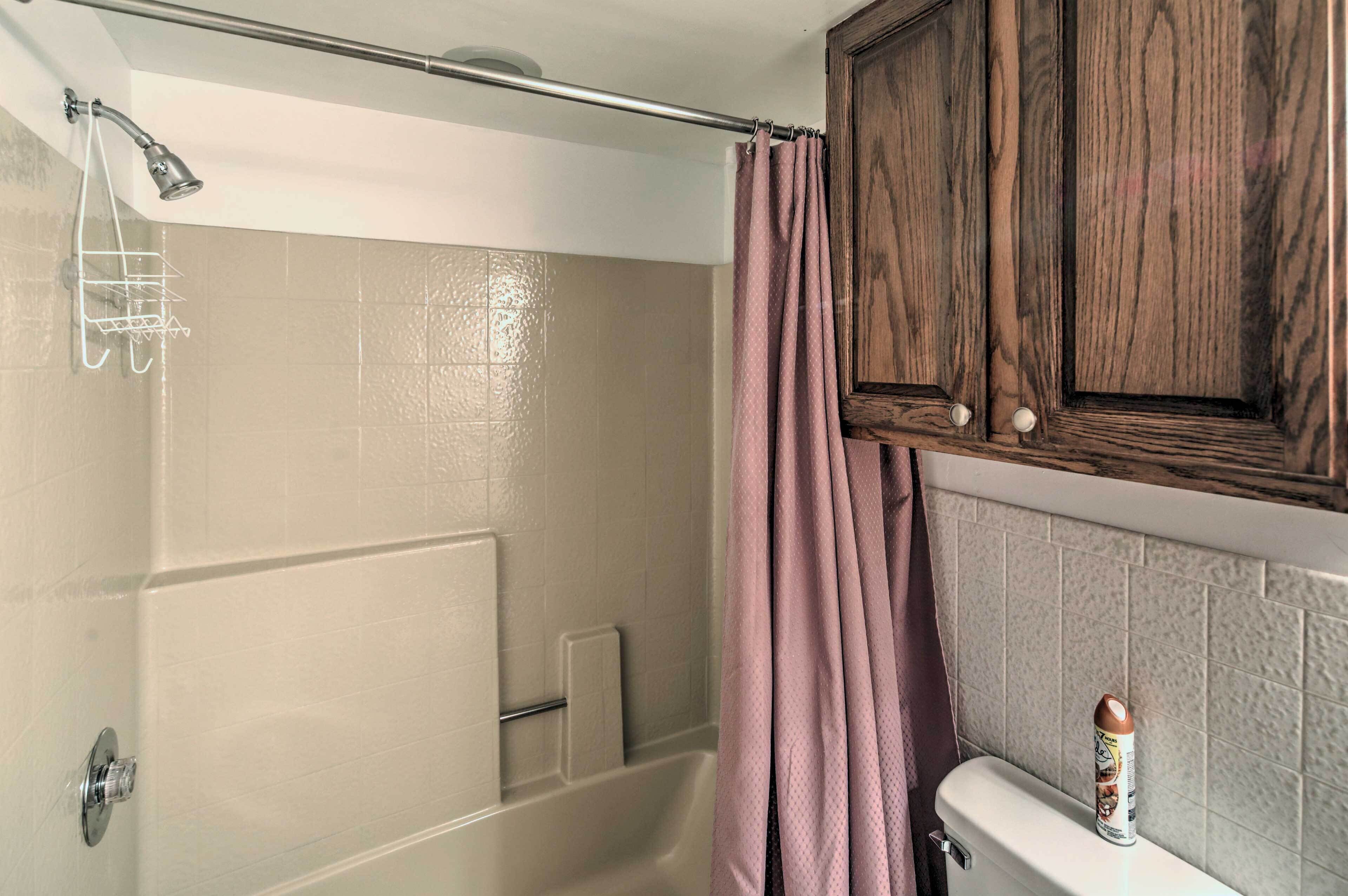 A bathroom with a shower, a toilet, and a cabinet.