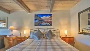 A bedroom with a large bed, two nightstands, a mirror, and a painting of a mountain landscape. - Pool + Hot Tub Access! Ski Lovers Studio (Snowmass Village)