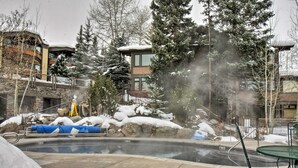 A heated outdoor pool surrounded by snow-covered rocks and trees. - Pool + Hot Tub Access! Ski Lovers Studio (Snowmass Village)