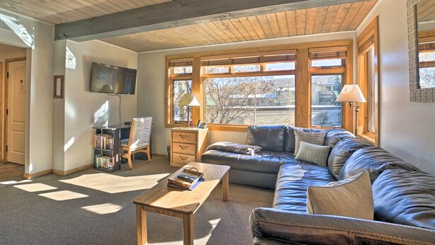 A cozy living room with a leather sofa, wooden coffee table, and a bookshelf. - Pool + Hot Tub Access! Ski Lovers Studio (Snowmass Village)
