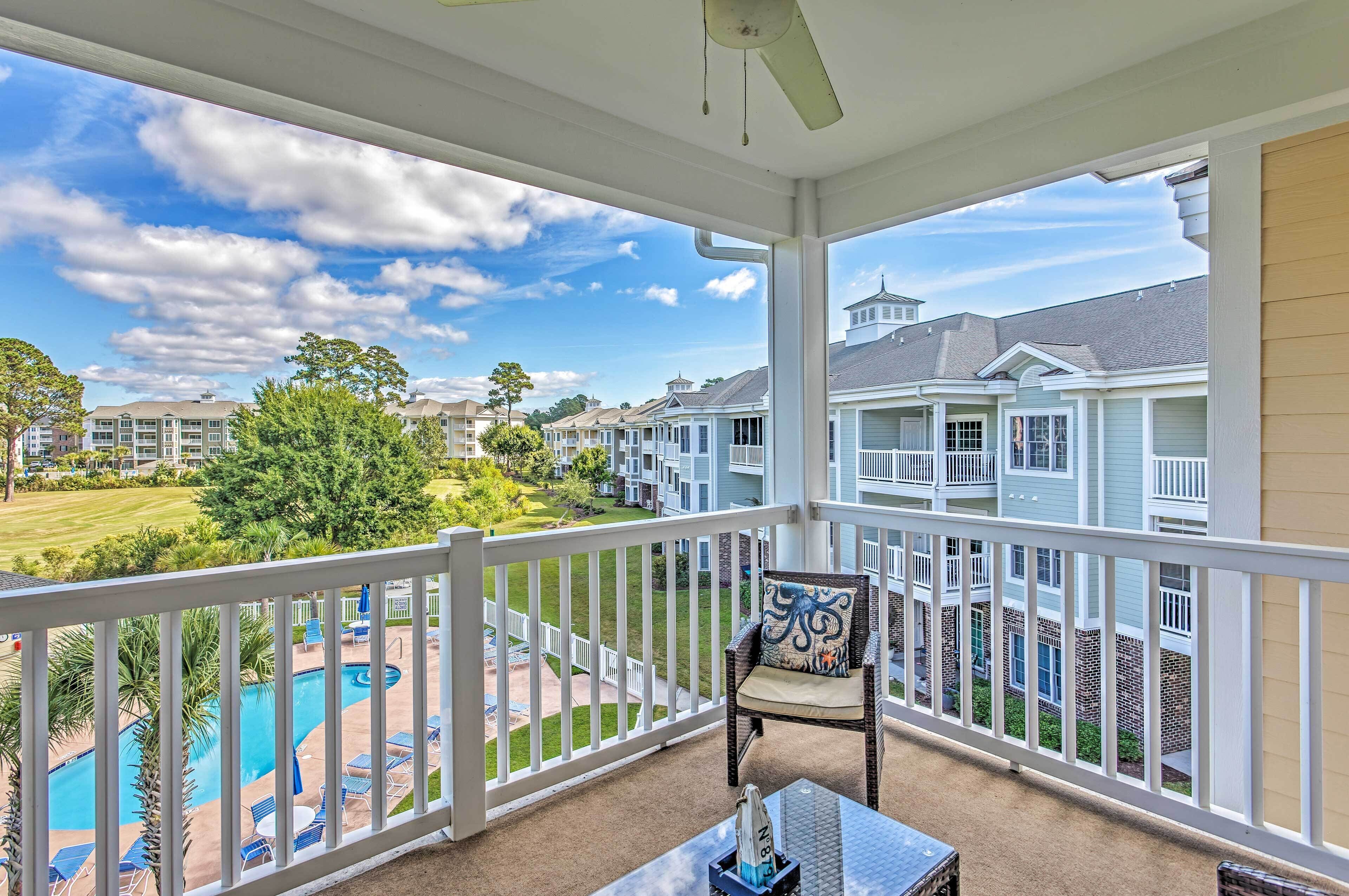 A balcony with a view of a swimming pool and a lawn.