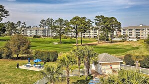 Um campo de golfe com um clube e um edifício residencial ao fundo.