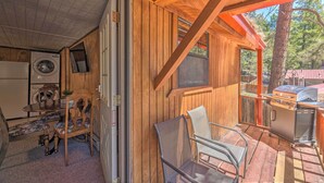Ein Holzblockhaus im Inneren mit Küche, einer Essecke mit Tisch und Stühlen und einem Grill draußen.