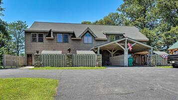 A two-story house with a covered porch, a stone foundation, and a wooden fence.