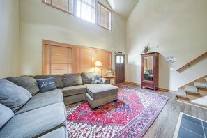 A living room with a sectional sofa, a patterned rug, a wooden cabinet, and a staircase. - Conneaut Lake Home With Yard, 1/2 Mi to Beach/park (Conneaut Lake)