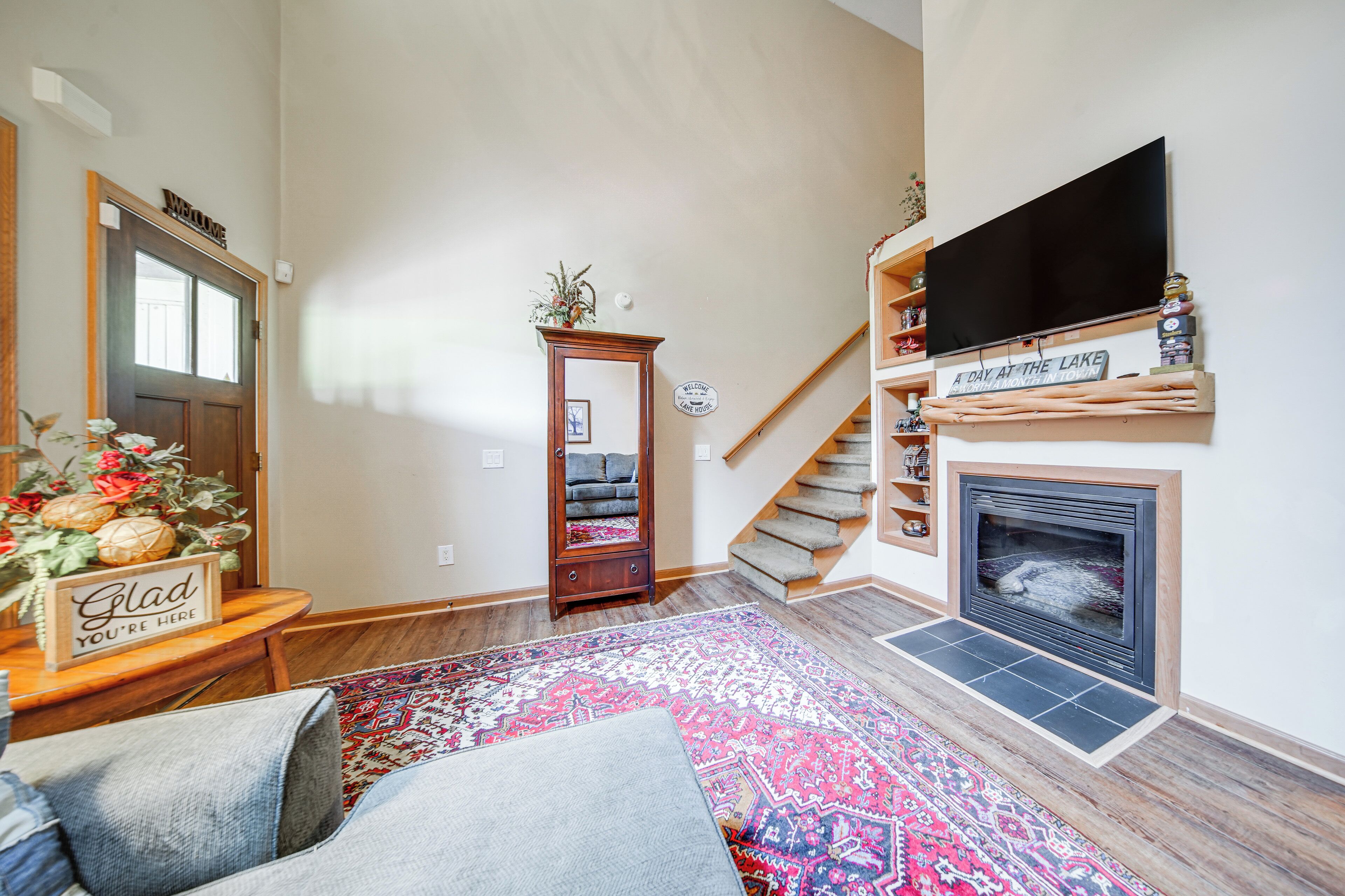 A living room with a fireplace, a staircase, and a flat-screen TV mounted above the fireplace.
