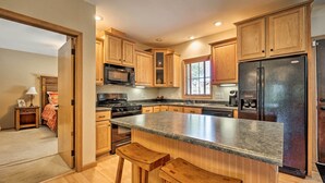 Una cocina moderna con armarios de madera, encimera de granito y refrigerador de acero inoxidable.