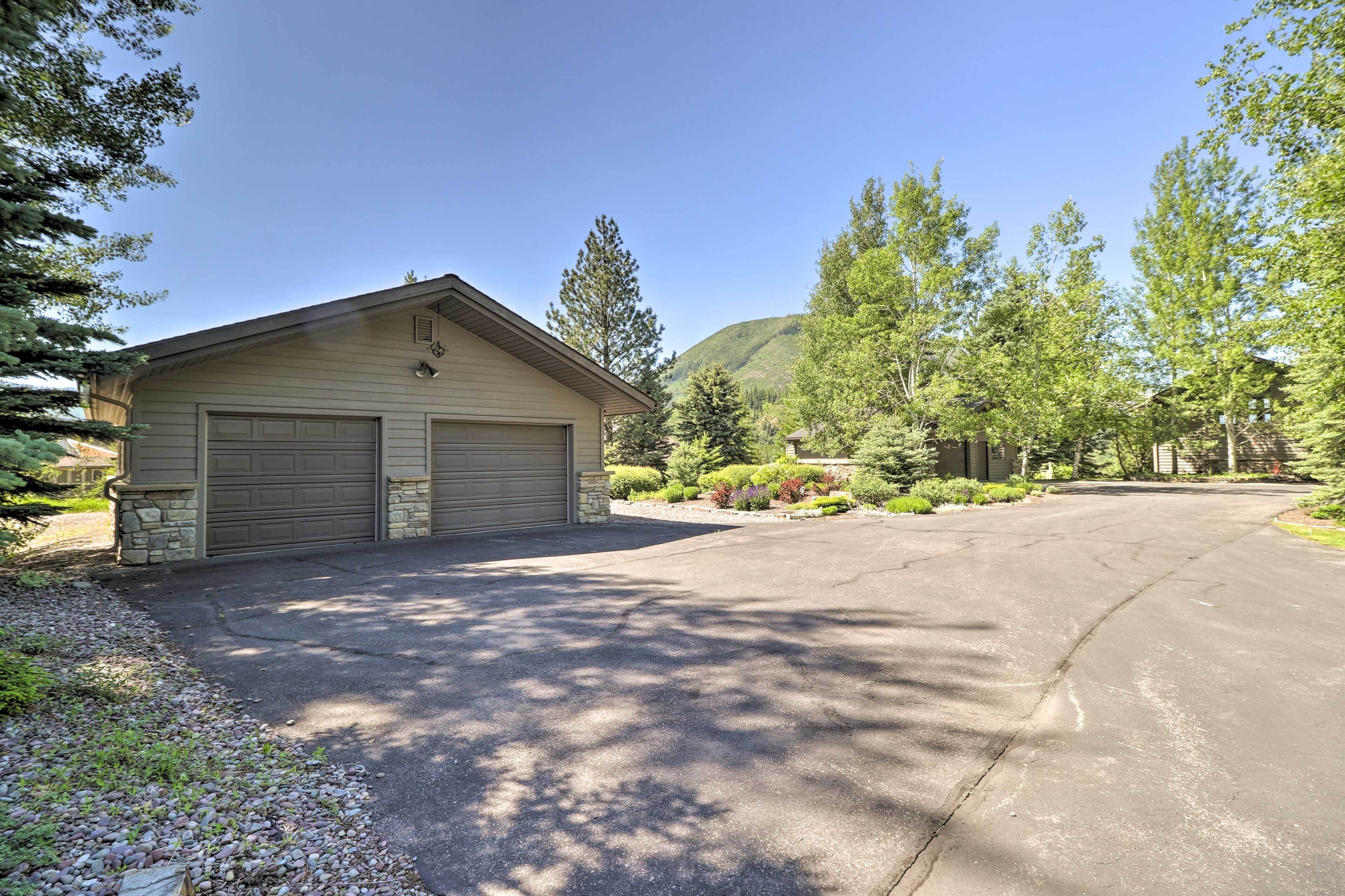 A two-car garage attached to a house with a driveway leading to a mountain backdrop.