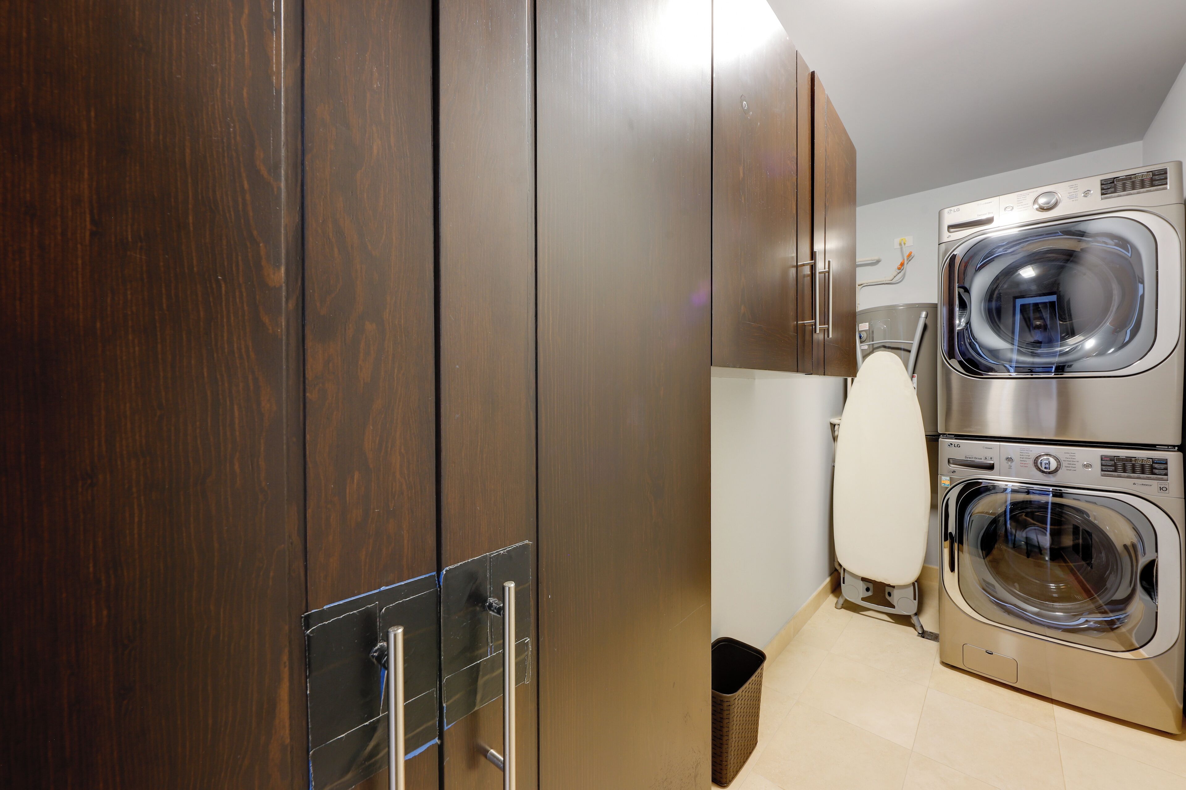 Une buanderie moderne équipée de deux machines à laver à chargement frontal, d’un sèche-linge et d’une grande armoire en bois.