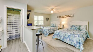 Slaapkamer met twee bedden, een plafondventilator, een raam en een bord met de tekst 'OAK ISLAND'.