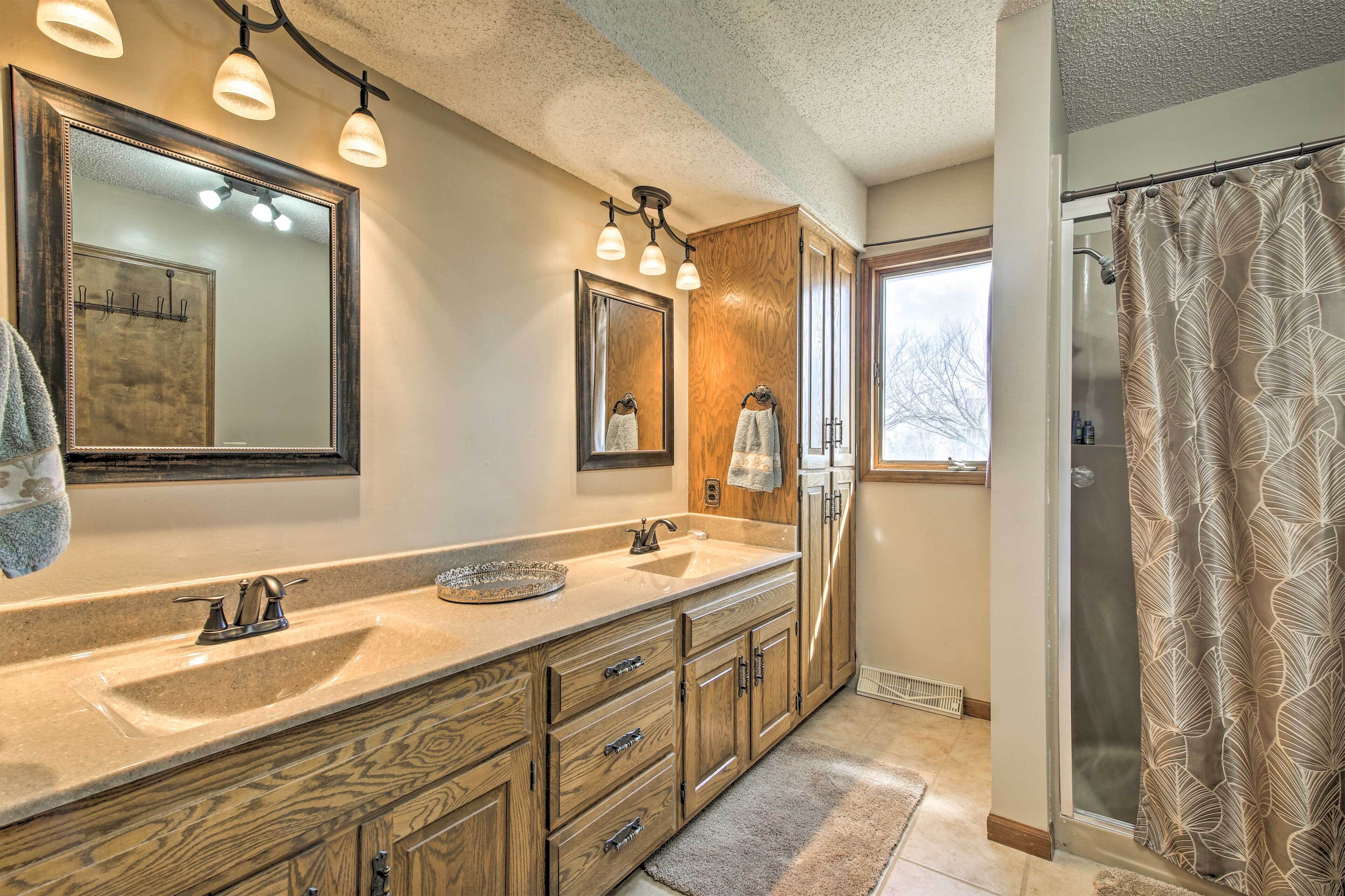 A bathroom with a large mirror, wooden cabinets, a sink, and a shower curtain.
