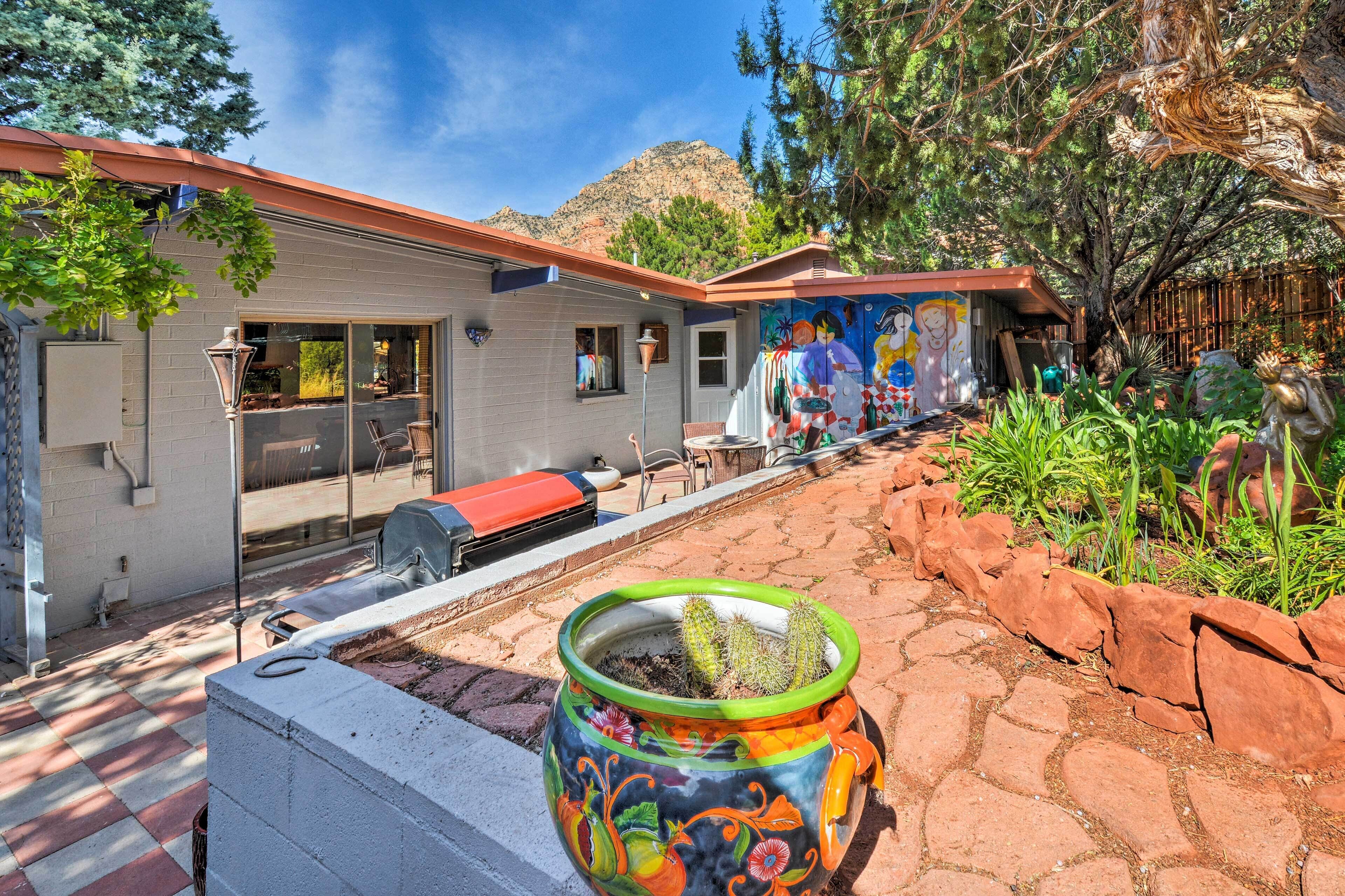 Un patio con una parrilla, asientos exteriores y una maceta decorativa con un cactus.