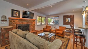 A spacious living room with a stone fireplace, leather sofas, and a coffee table. - Patio & Views: Peaceful Sedona Getaway! (Sedona)