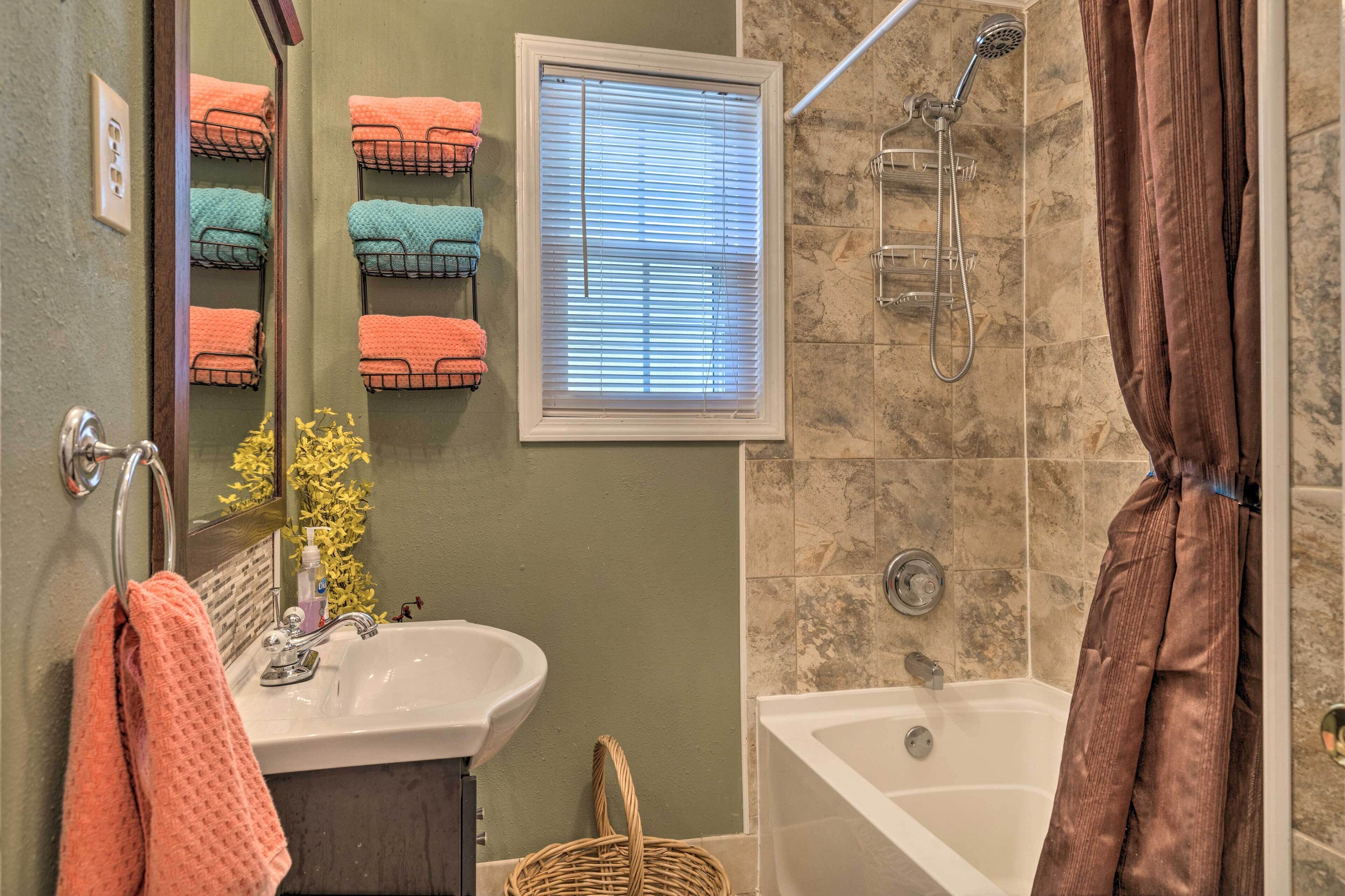 Ein Badezimmer mit Waschbecken, Spiegel, Handtuchhalter, Dusche und Badewanne.