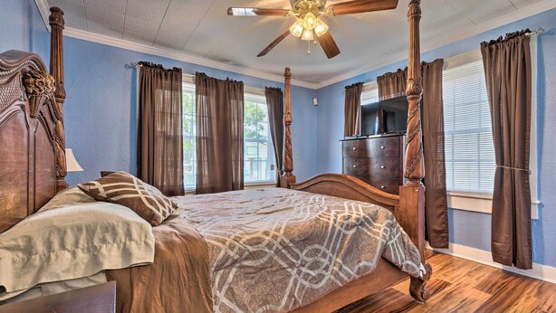 A four-poster bed with a canopy, wooden floor, and a ceiling fan.