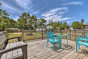 A wooden deck with a table and chairs, surrounded by a wooden fence and trees. - Cozy Gulfport Home: Walk to Beach, Marina & Casino (Gulfport)