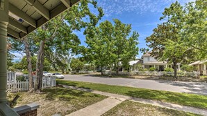 A residential street with houses, trees, and a sidewalk.