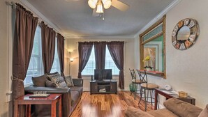 A living room with a sofa, a coffee table, a TV, and a dining area with a chair and table.