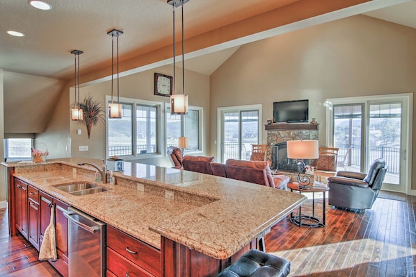 A spacious kitchen with granite countertops, a large island, and a dining area with a fireplace. - 'bella Greens' Spacious Sturgis Rally Home w/ Deck (Sturgis)