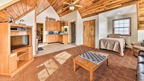 A spacious living area with a high ceiling, wooden beams, a television, a game table, and a cozy bed. - Ski-in/ski-out Ghent Cabin w/ Mountain Views! (Ghent)