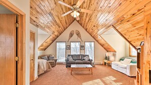 A spacious loft-style living room with a high ceiling, wooden beams, and a large ceiling fan. There are two sofas and a coffee table in the center, with large windows providing natural light. - Ski-in/ski-out Ghent Cabin w/ Mountain Views! (Ghent)
