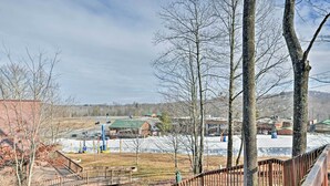 A view of a park with a wooden bridge, trees, and a distant building with a green roof. - Ski-in/ski-out Ghent Cabin w/ Mountain Views! (Ghent)